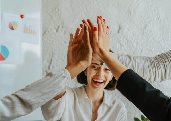 Happy colleagues high-fiving in a meeting, showcasing teamwork and success.